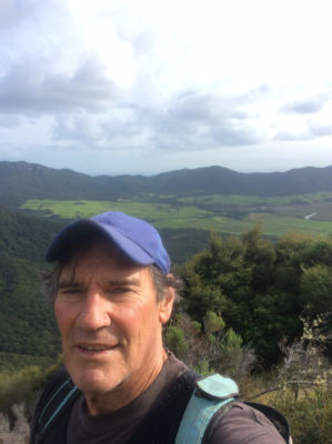 A selfie of a man on a bush covered hillside