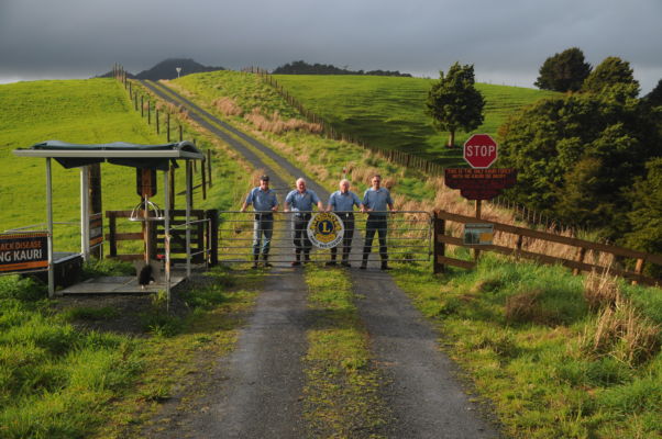 Four people stand behind a farm gate
