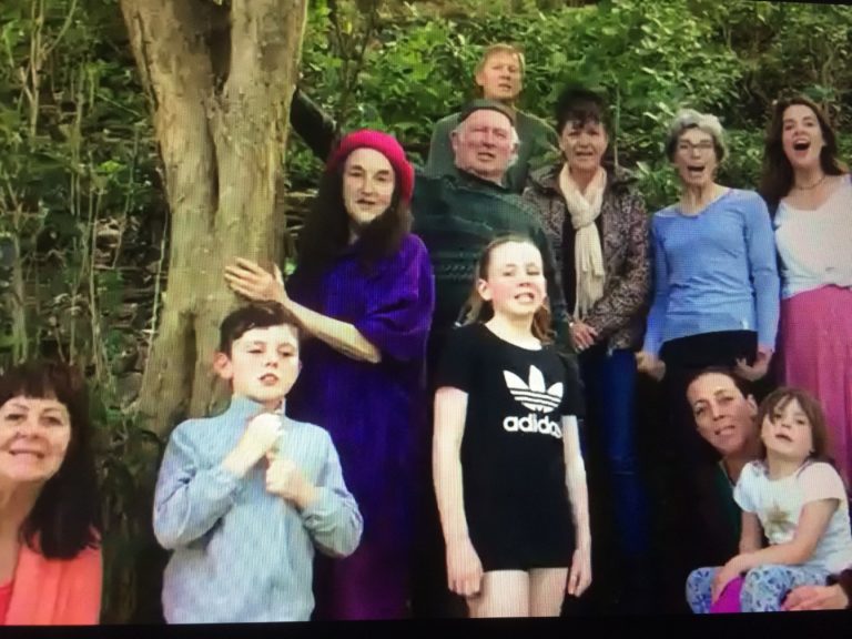 A group of children and adults stand around a tree