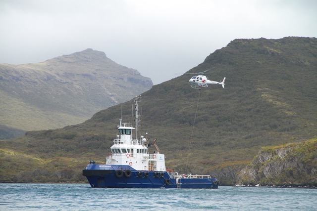 A helicopter takes gear from a boat