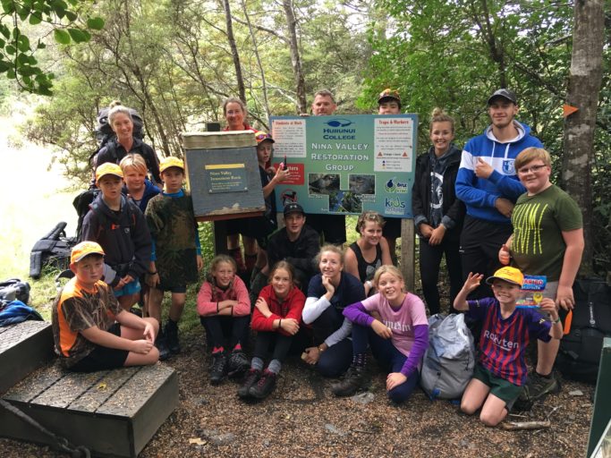 Students on a weekend trip beside public signage explaining their Nina Valley restoration work.
