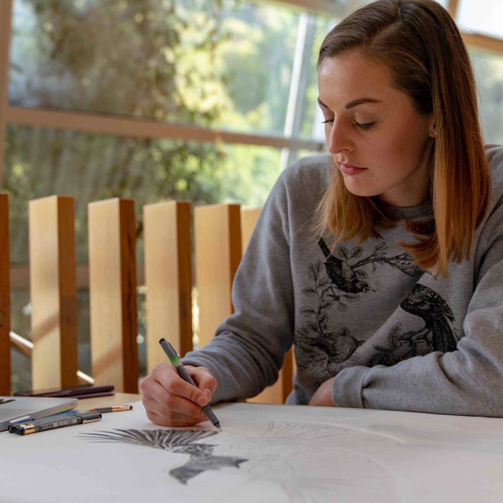 Photo of Hannah drawing a bird by hand