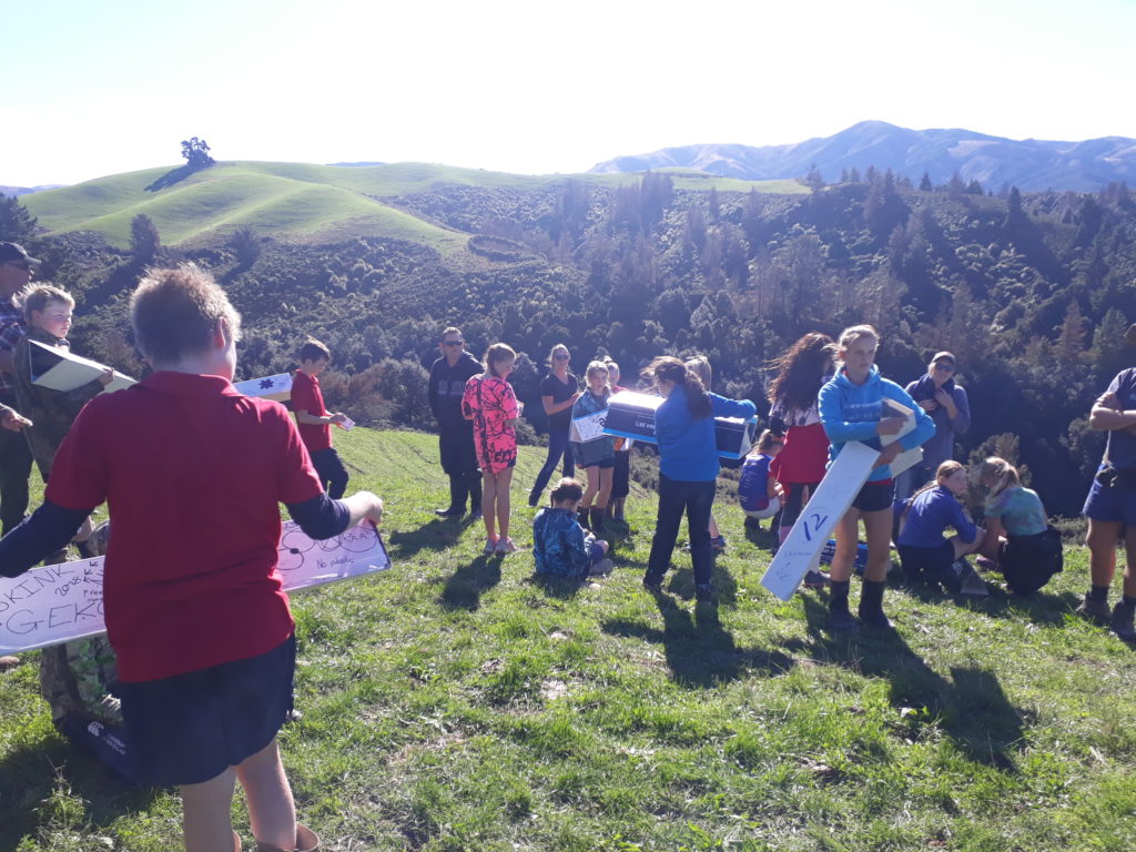 A group of school kids on a grass covered hillside with tracking tunnels. The are at White Rock.