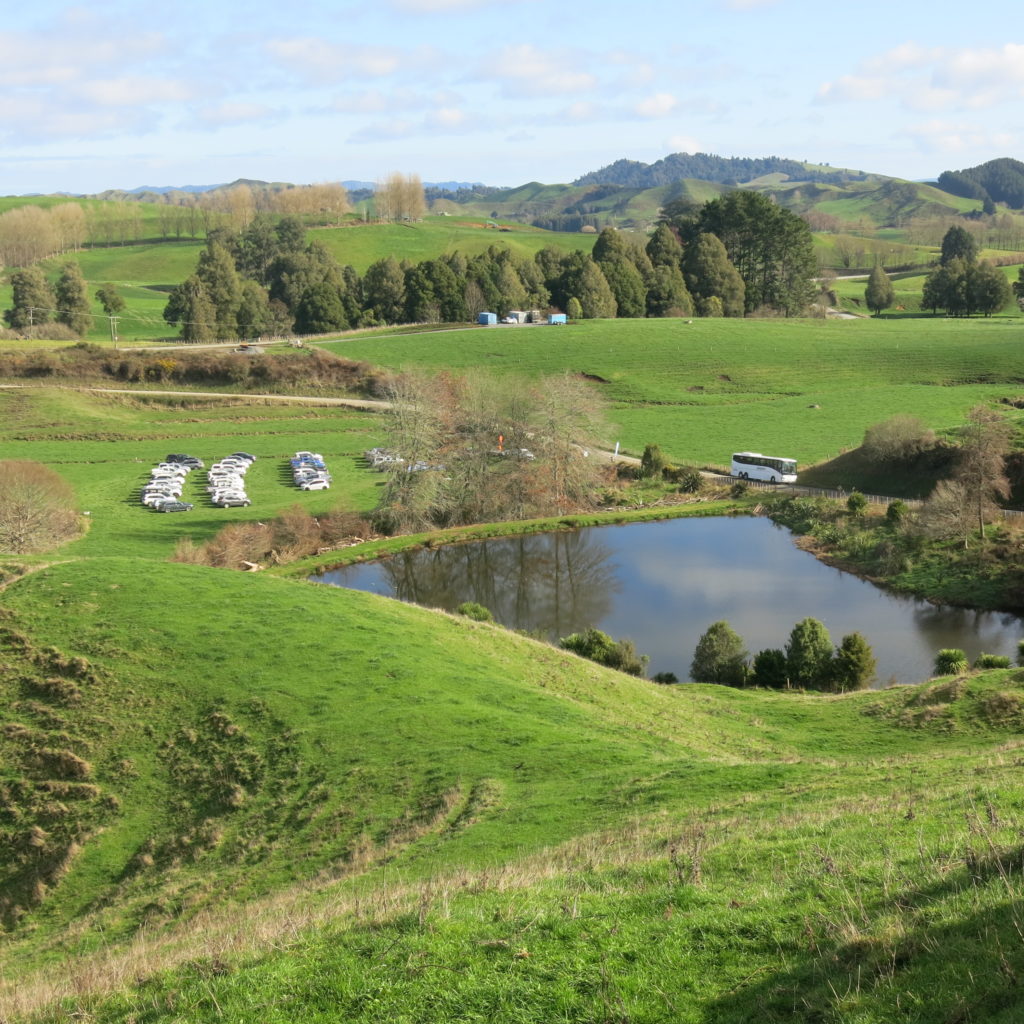 A landscape photo of green hills and a small pond