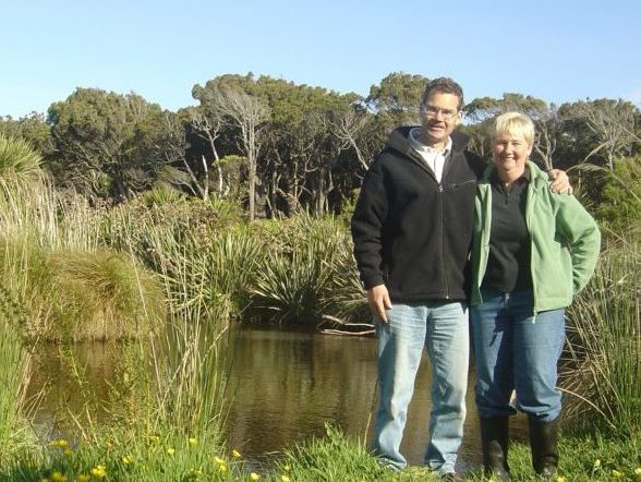 Chris and Brian next to a pond with greenery and blue sky