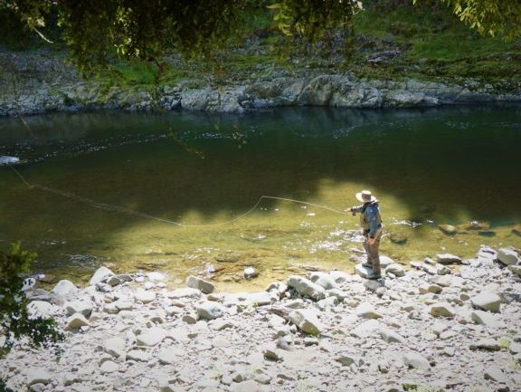 A trout fisher on the side of a river