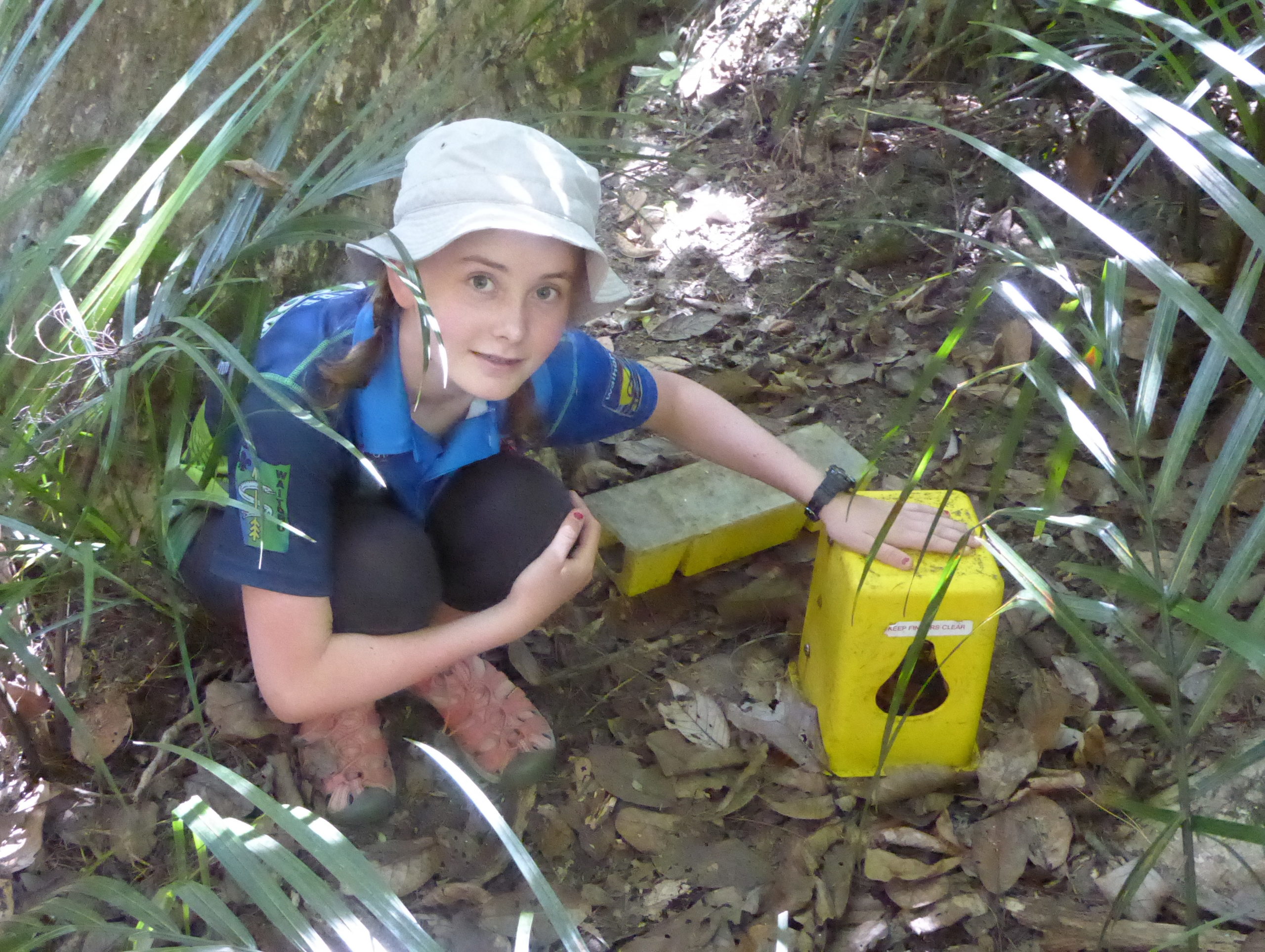 A child crouches by a trap in the bush