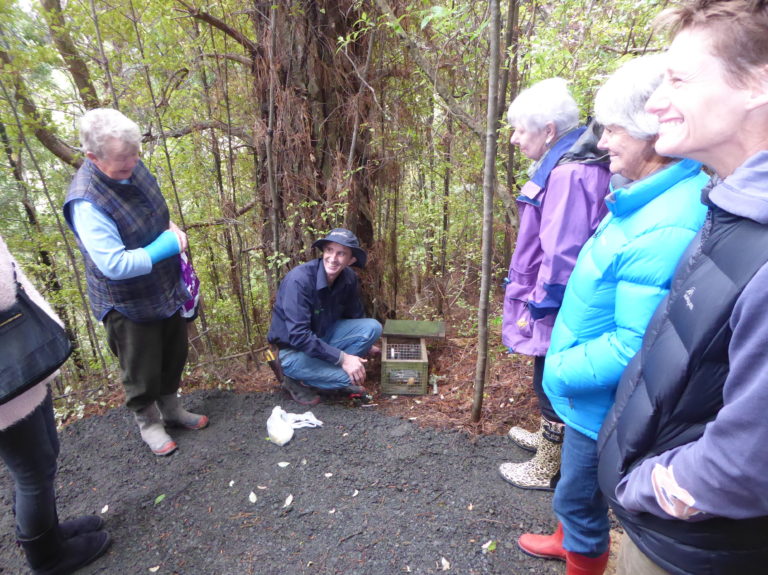 People stand in a group around a trap demonstration