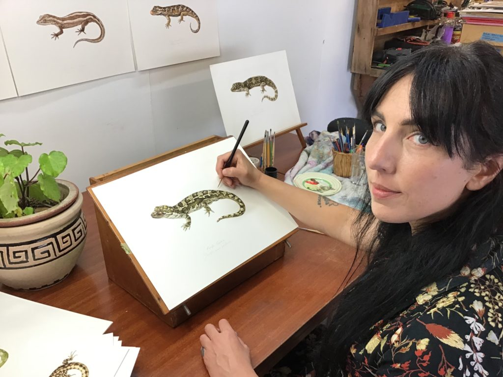 Erin working on a lizard painting in her studio.