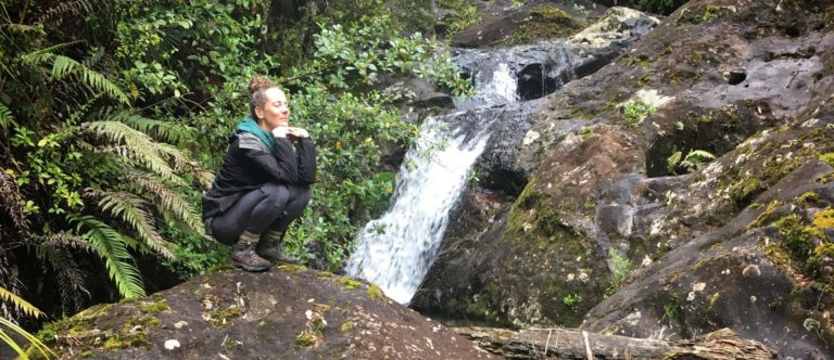 Sara on a boulder in a forest.