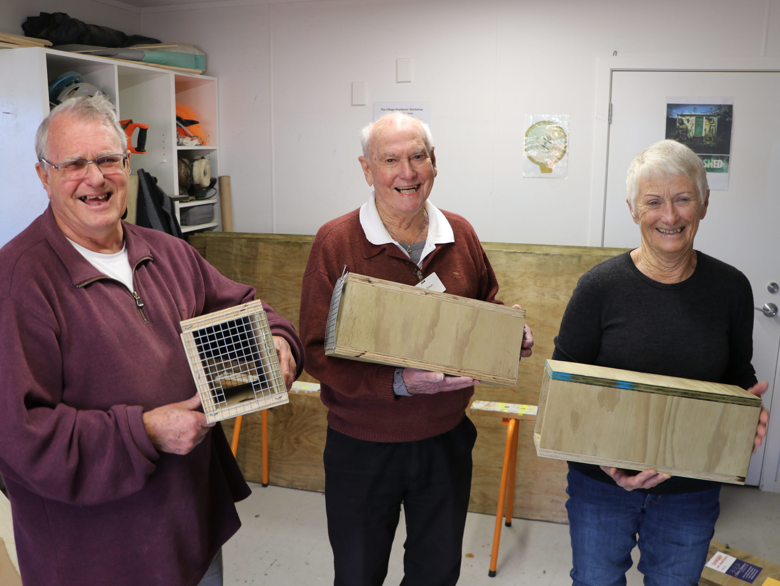 Three people holding trap boxes.