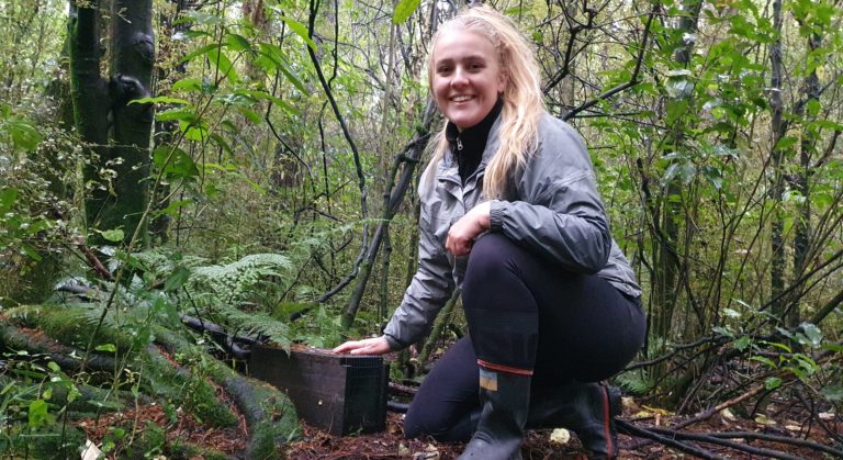 Jade with a trap box in the forest.