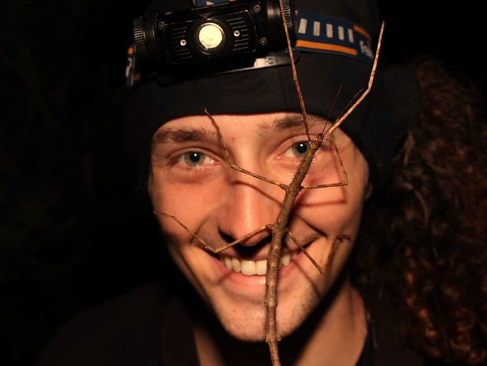 Smiling man with stick insect on his face 