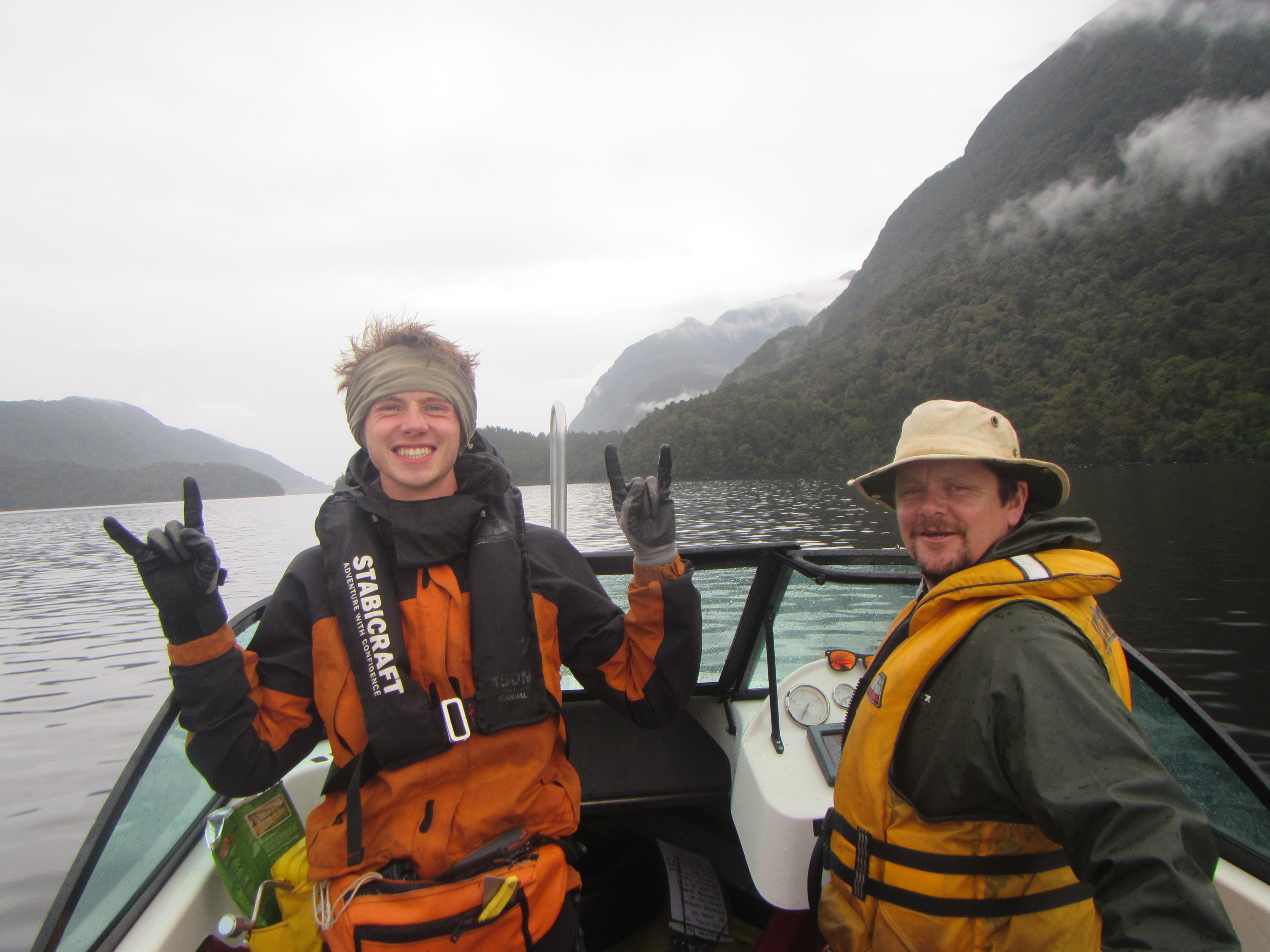 Two men in lifejackets smiling on a dinghy.