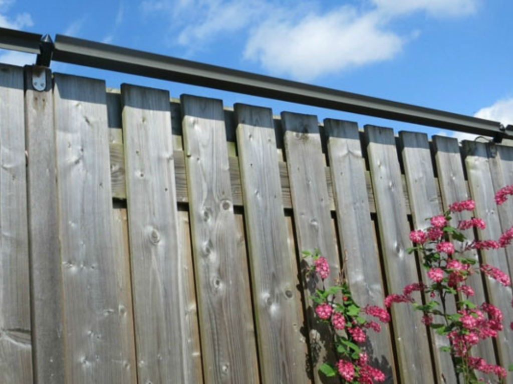 A backyard fence with cat-proof paddles on top