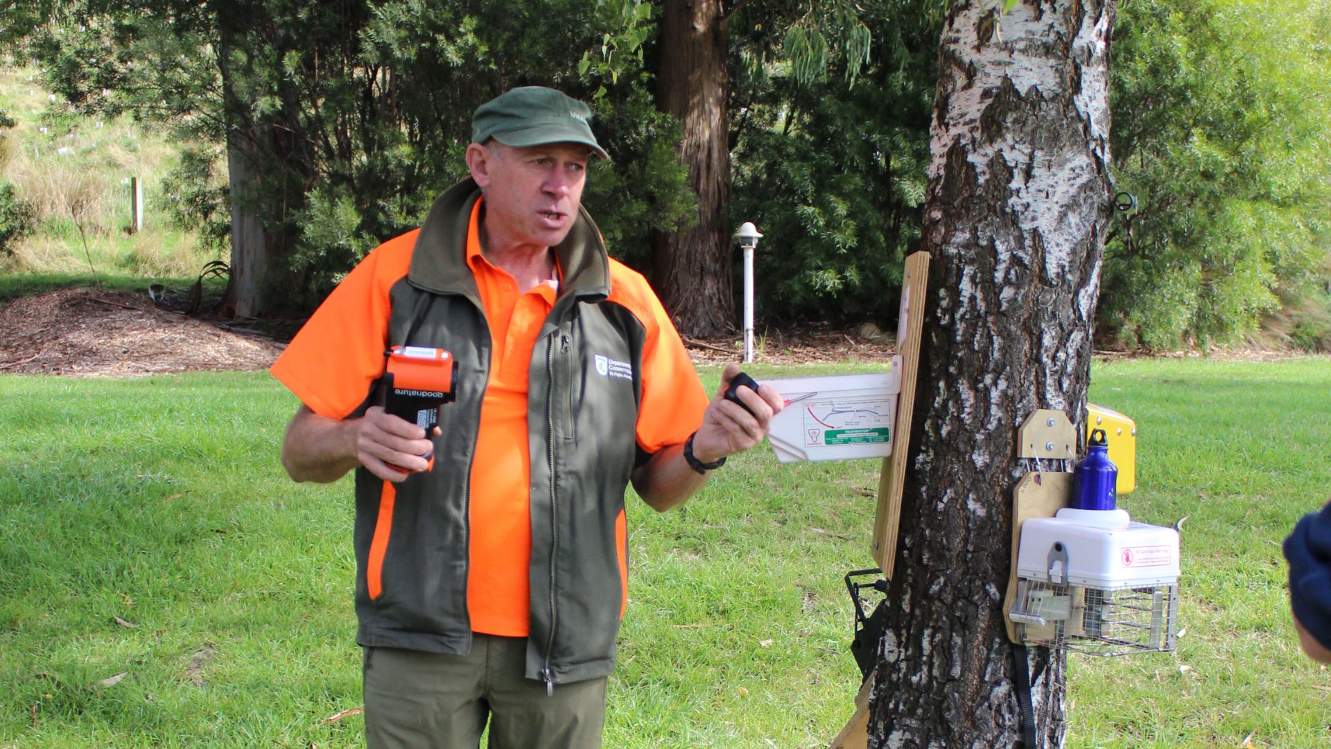 DOC predator free ranger Tim standing by a tree with heaps of traps