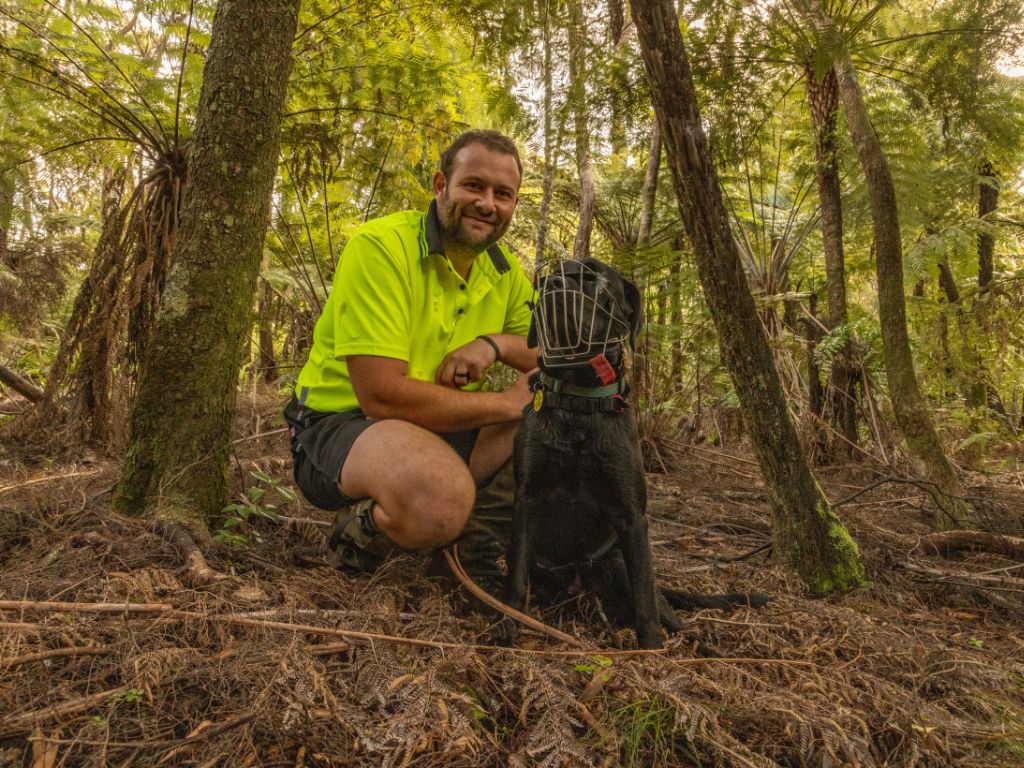 Operations manager Chris Giblin and Max the dog sit in the forest.