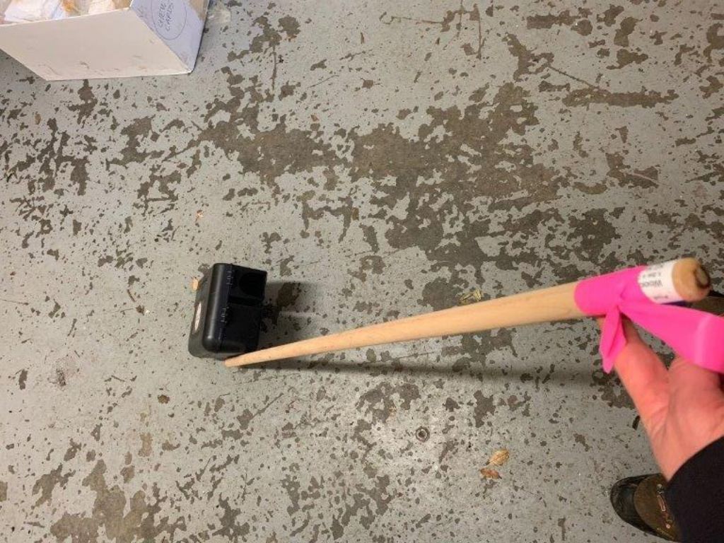 A bait station attached to the end of a broomstick
