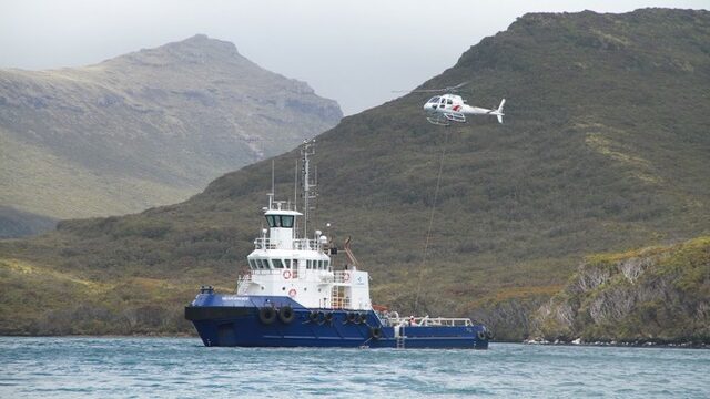 A helicopter takes gear from a boat