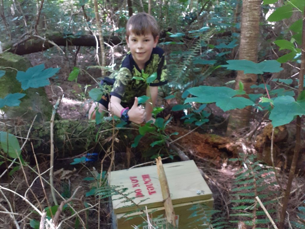 Harry crouching next to a trap box in the bush.