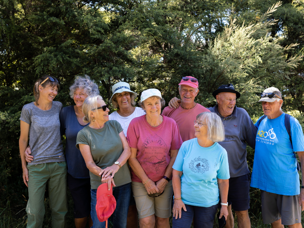 People smiling at each other for a group photo in the bush