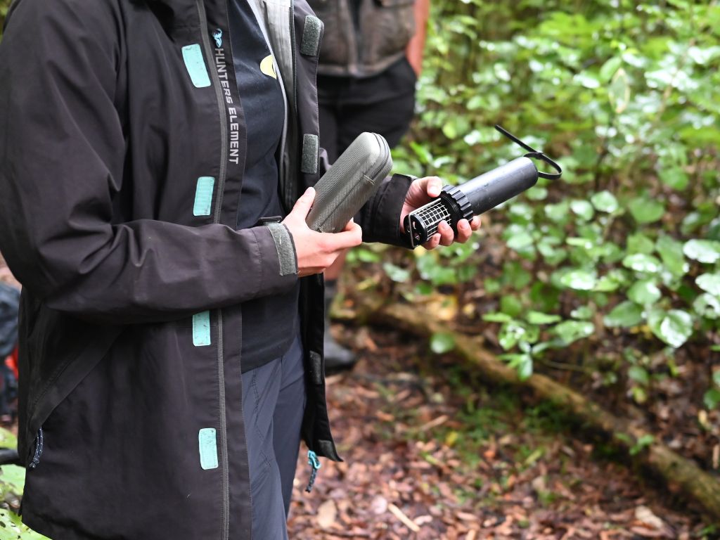 Emma standing in the bush holding a bat detector.