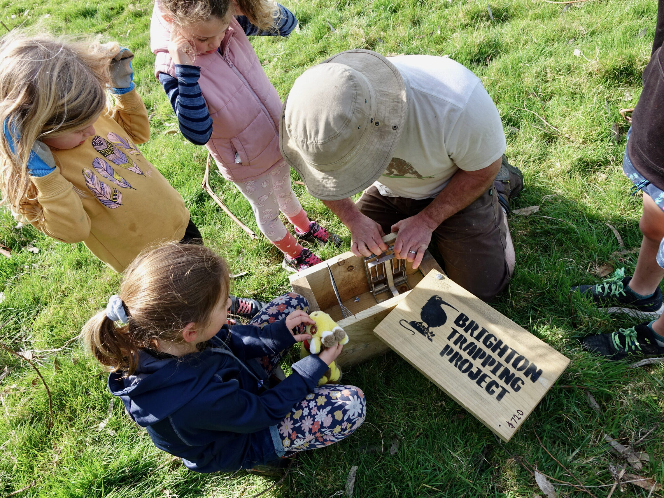 A man opening a wooden trap, showing children the inside.