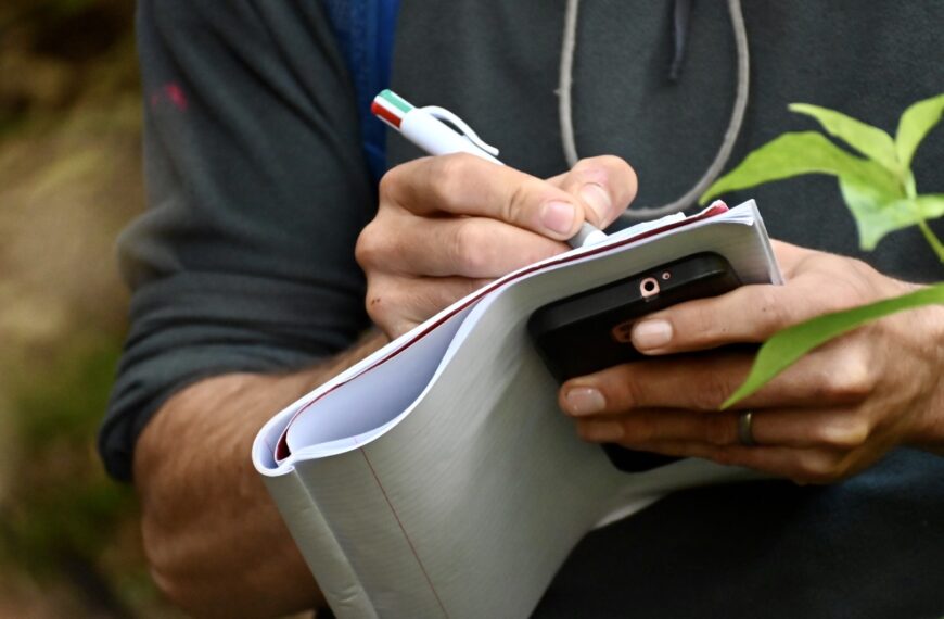 A person writing with a pen in a notebook