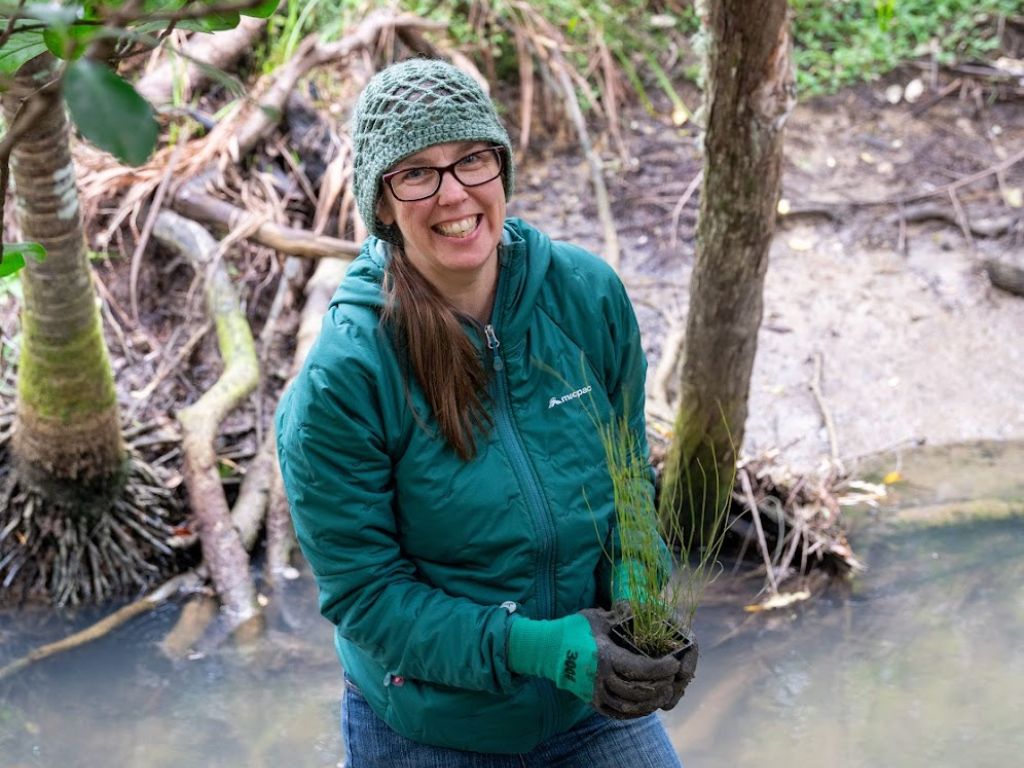 Woman planting trees along a stream