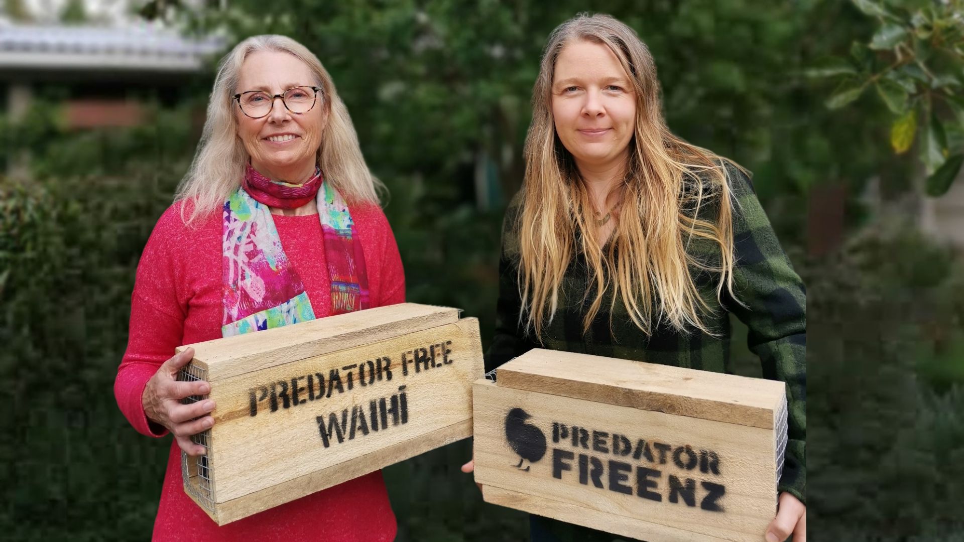 Two women smiling holding wooden trap boxes