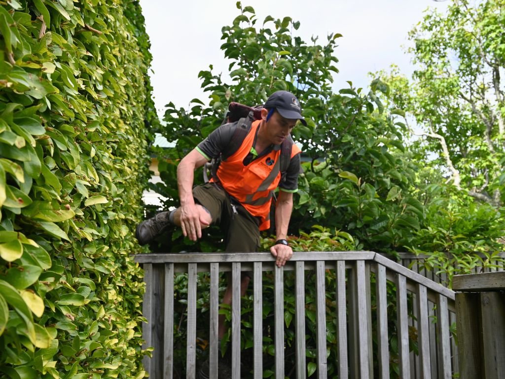 A man jumps over a wooden fence