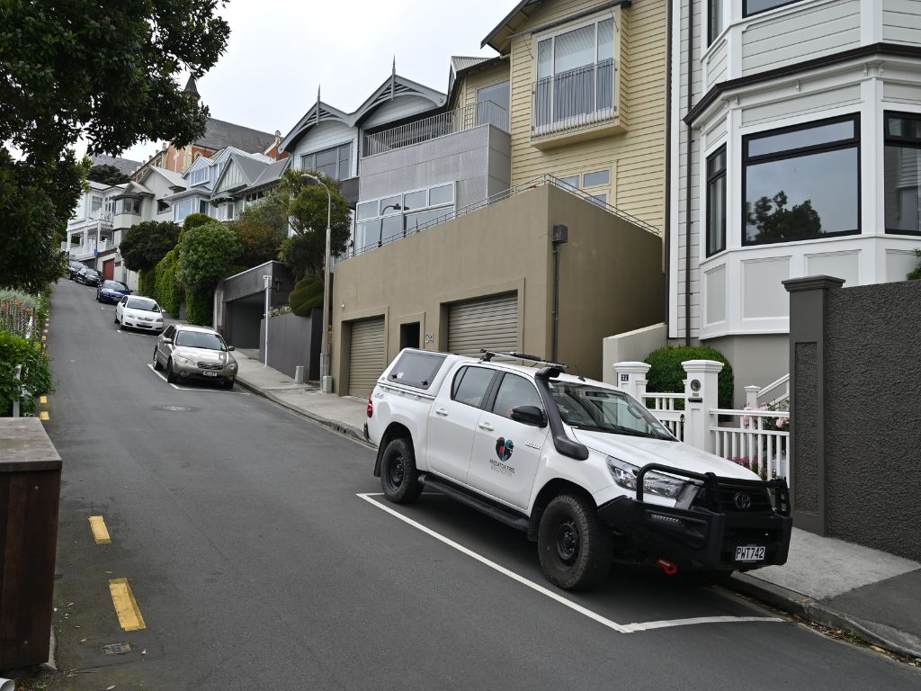 A white Predator Free Wellington ute parked on a steep street in Wellington