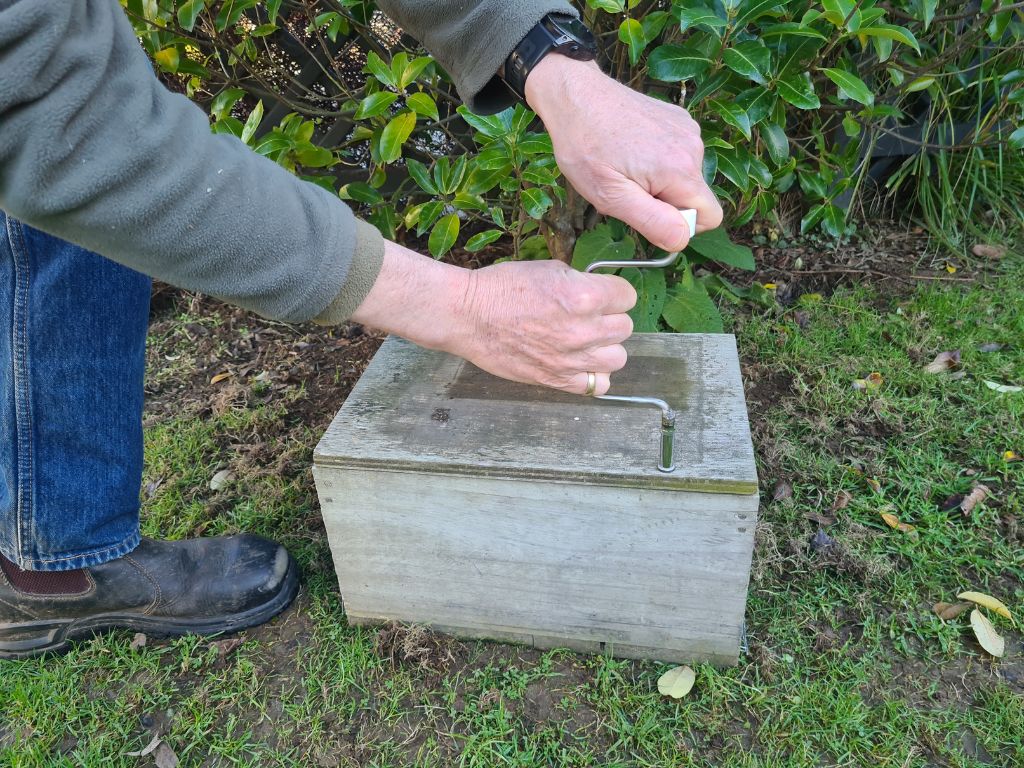 A speed wrench being used to open a DOC 200 trap box.