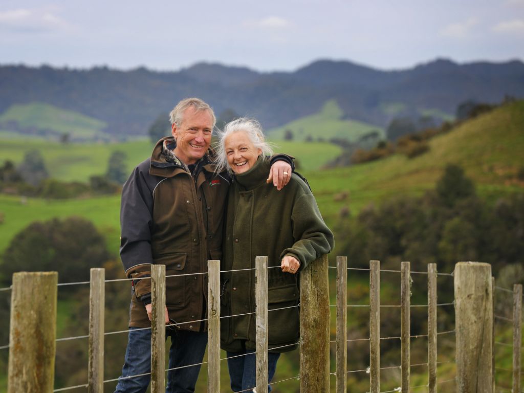 A couple standing behind a farm fence