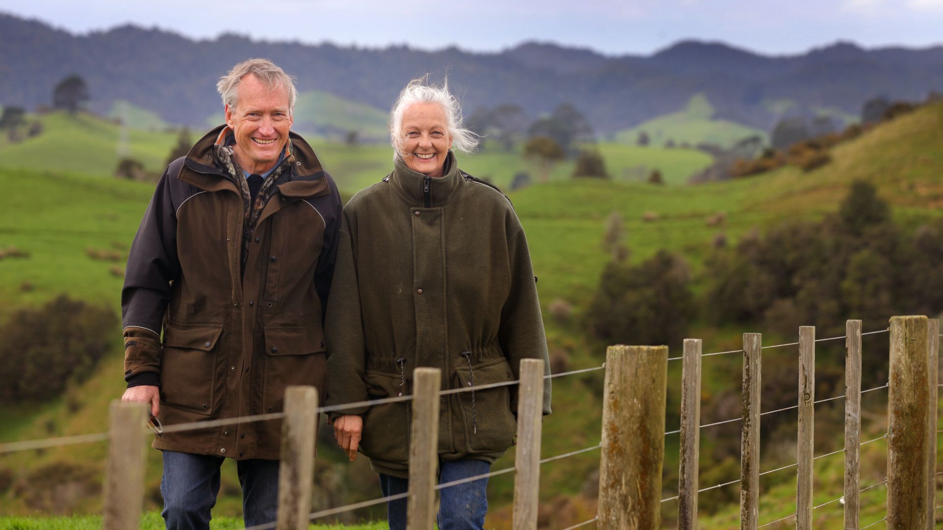 A couple standing behind a farm fence
