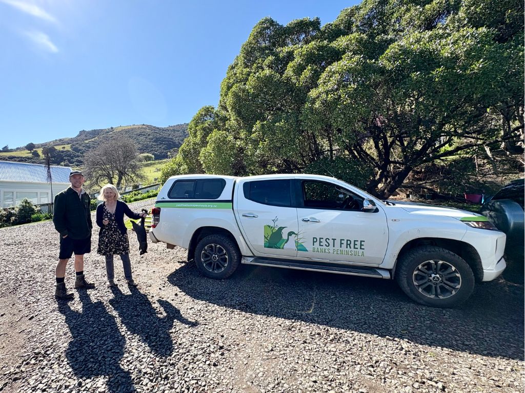 People standing next to a ute, holding a possum.