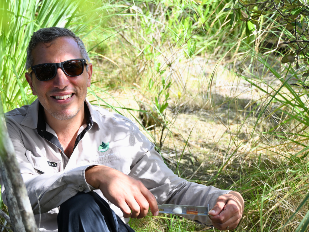 A man wearing sunglasses holding a metal lure tray