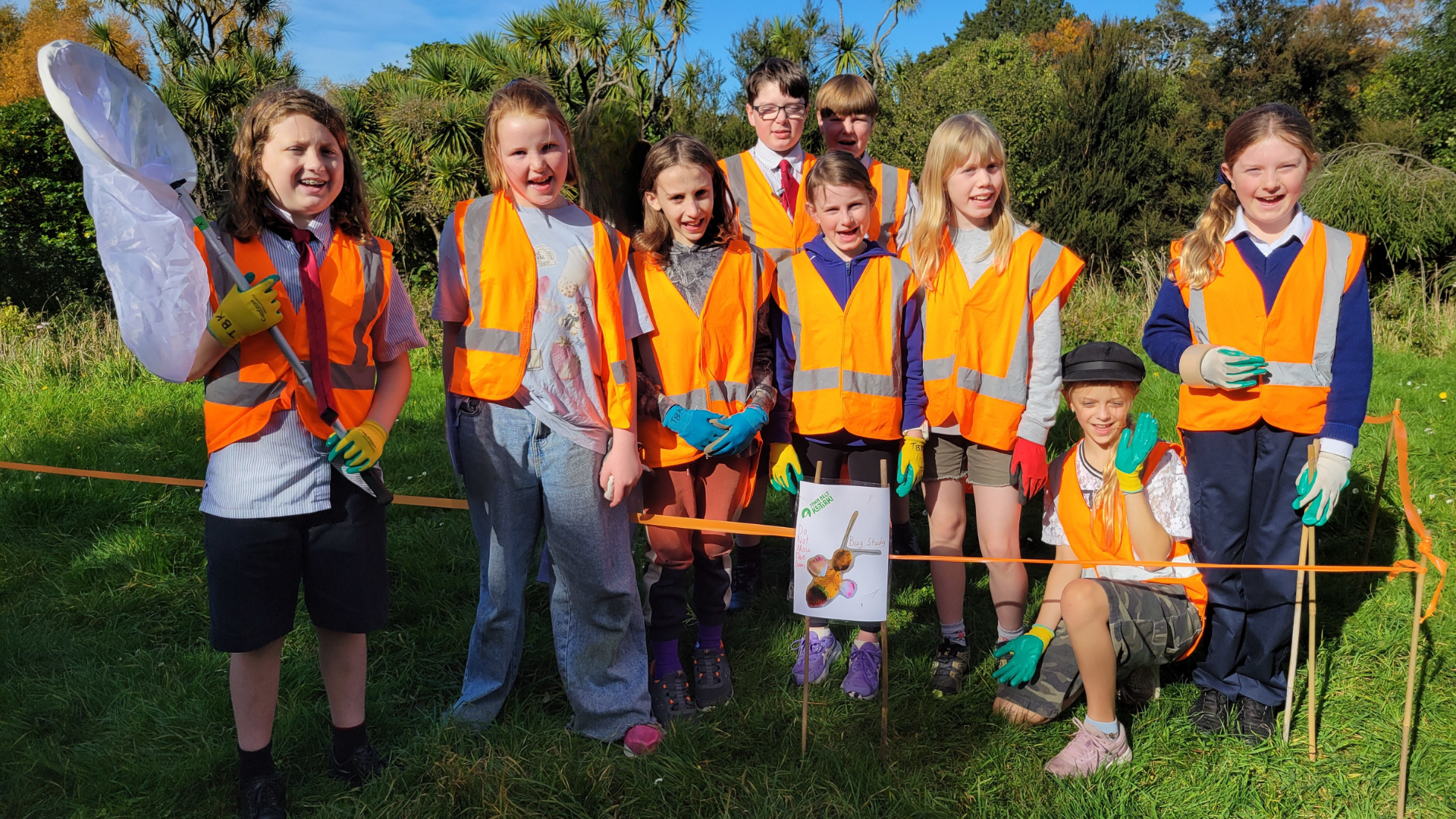 A group of children in hi-vis vests in the bush.